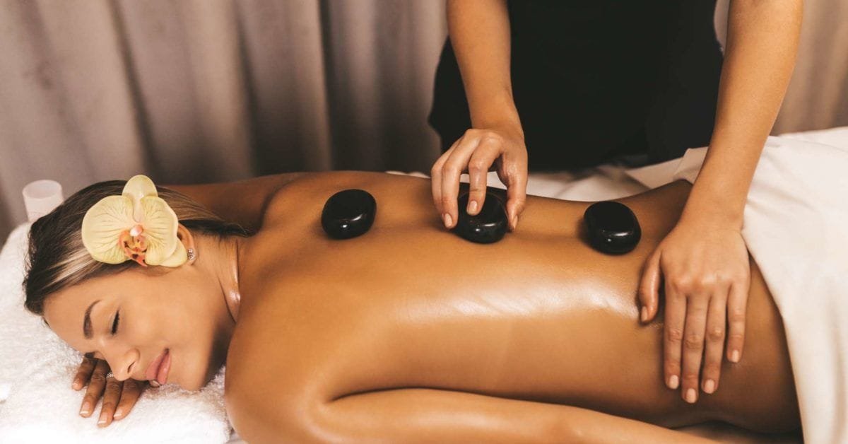 Therapist using smooth hot stones during a back massage.
