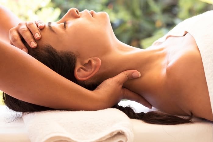 Therapist supporting a client’s neck and massaging her head.